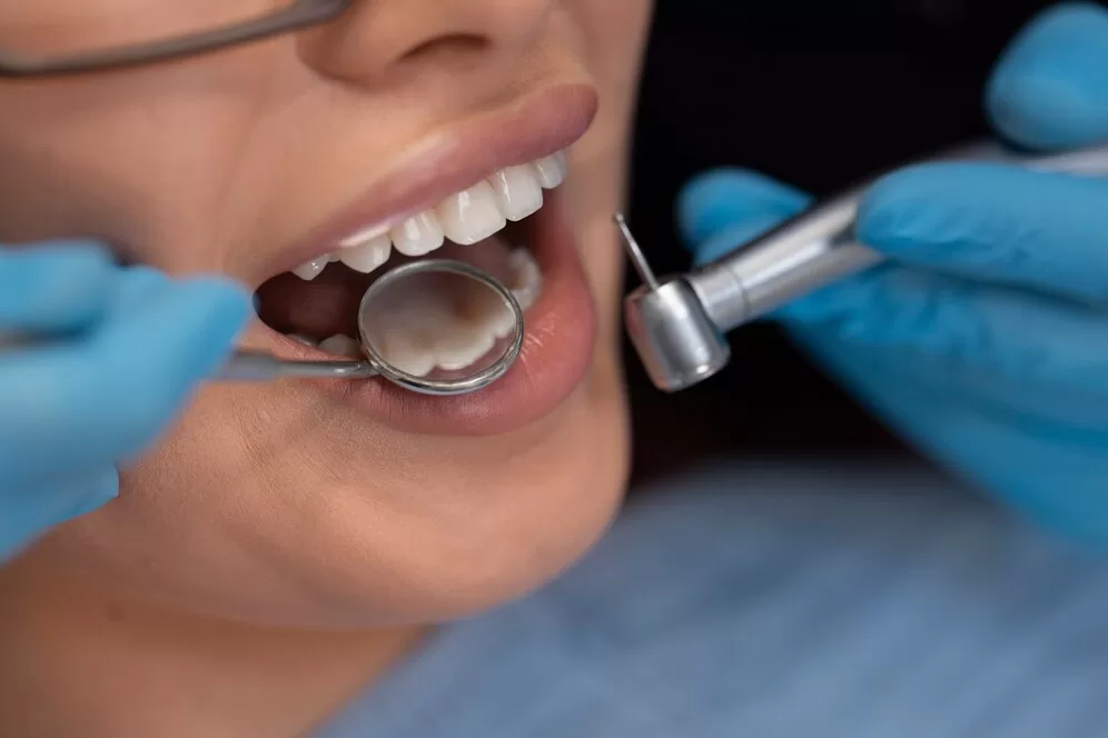 A close up of a dentist holding instruments near a patients mouth.