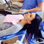 A dentist is getting ready to examine a female patient's teeth.