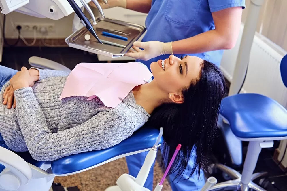 A dentist prepares to examine a female patient's teeth, ensuring the tools are ready for a thorough check-up.