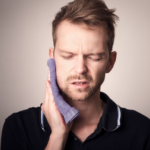 A man experiencing tooth pain, holding his jaw in discomfort and showing signs of distress from the ache.