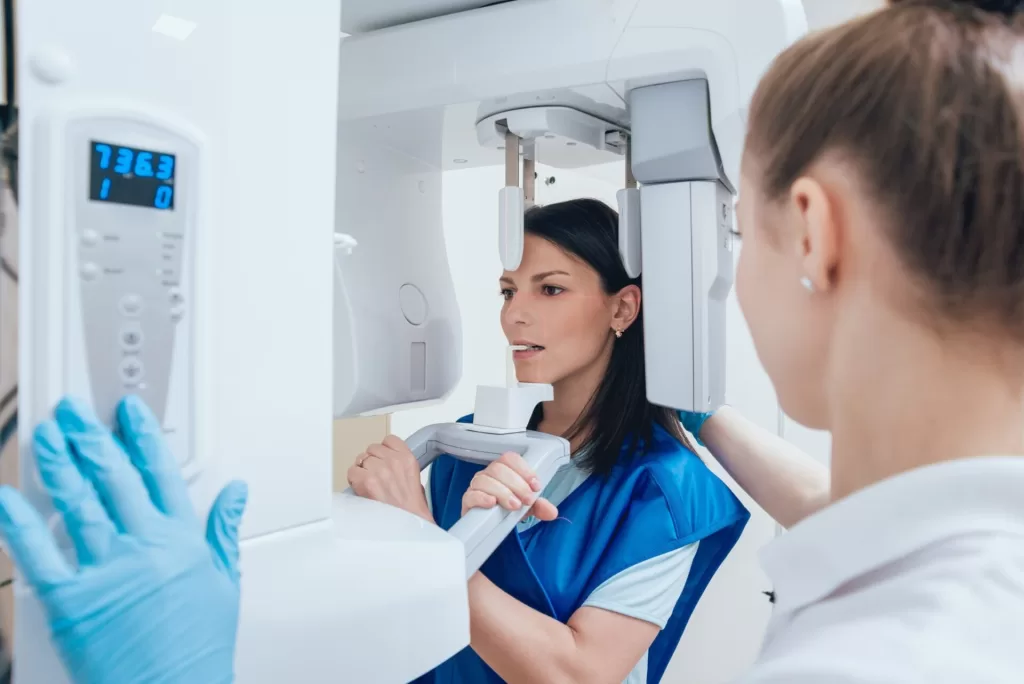 Dental assistant operating a CBCT 3D dental imaging scanner for detailed dental diagnostics.