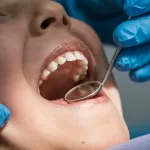 A dentist treats a patient's teeth, performing a procedure with professional tools to address dental issues.