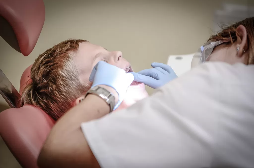 A kid gets his teeth examined by a dentist, ensuring proper oral health and addressing any potential dental issues.