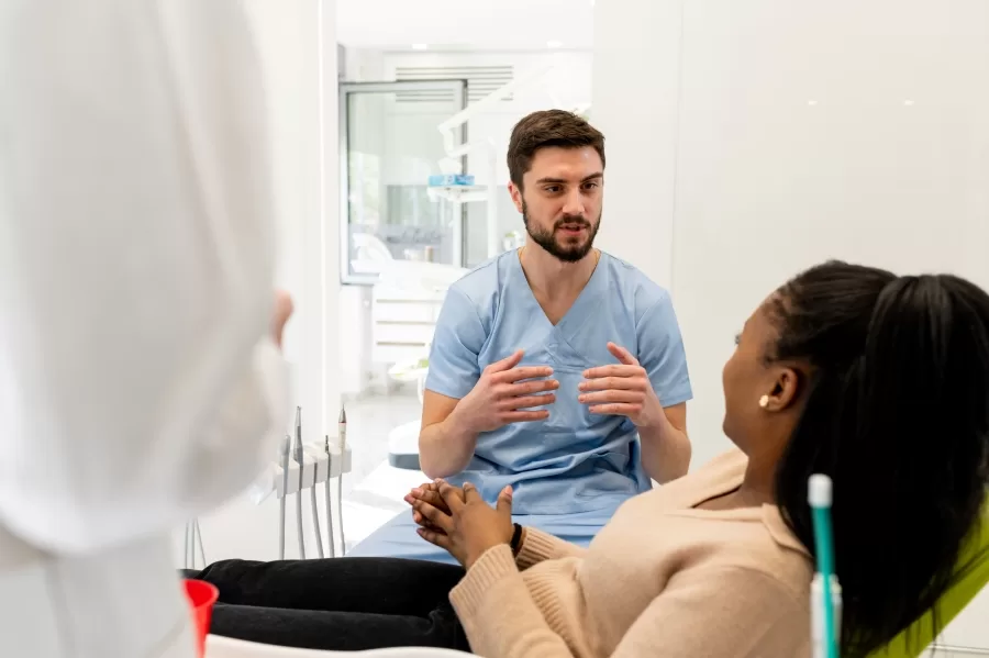 Dentist in blue robe consulting patient about wisdom teeth extraction options at Ridge Oral Surgery in New Jersey.
