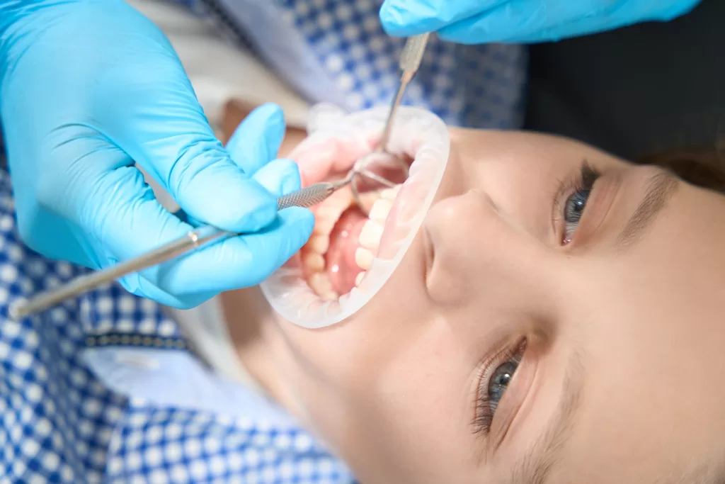 A close-up of a dentist examining a patient's teeth, possibly preparing for a bone graft and implant procedure on the same day.