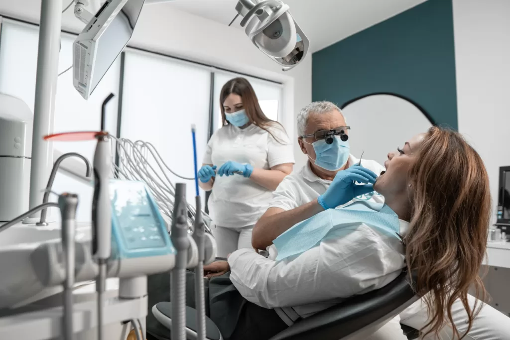 Oral surgeon consulting with a patient while assistant prepares instruments in a state-of-the-art dental implant room.