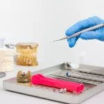 A dental tray with tools, including a gloved hand holding an instrument, likely for a bone graft and implant procedure on the same day.