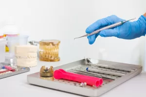 A dental tray with tools, including a gloved hand holding an instrument, likely for a bone graft and implant procedure on the same day.