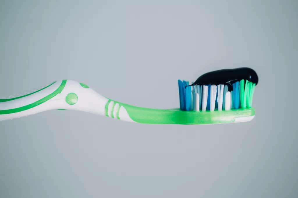 A toothbrush with black charcoal toothpaste on the bristles. This is a popular choice for people with dental implants to maintain good oral hygiene.