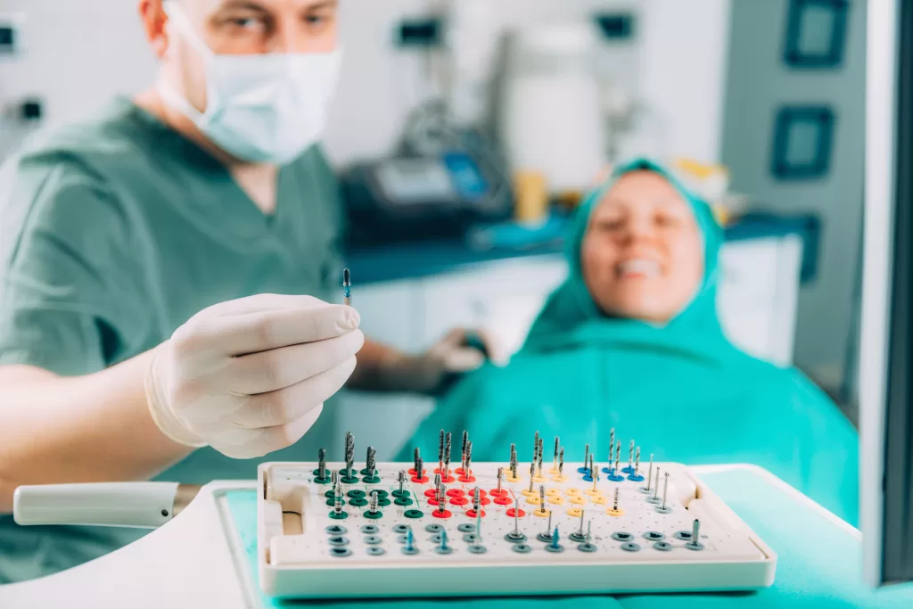 A dentist operating on the patient with specific dental tools used to replace teeth in human