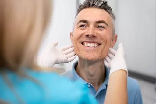 Close-up image of a doctor checking a man wearing safety gloves.