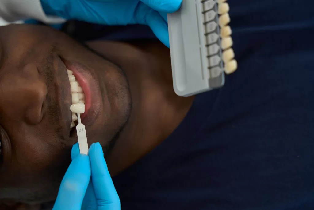 A dentist matches a patient's tooth color using a shade guide to prepare for dental implants. 