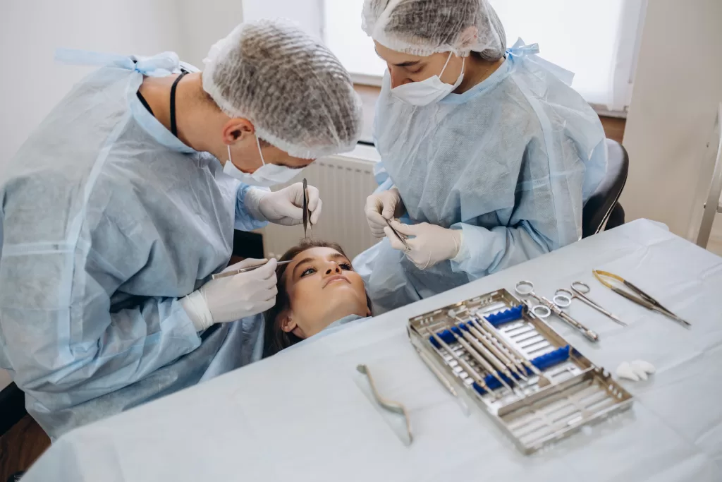 Two oral surgeons in protective gear performing a detailed procedure on a patient at a specialized oral surgery practice in Morristown.