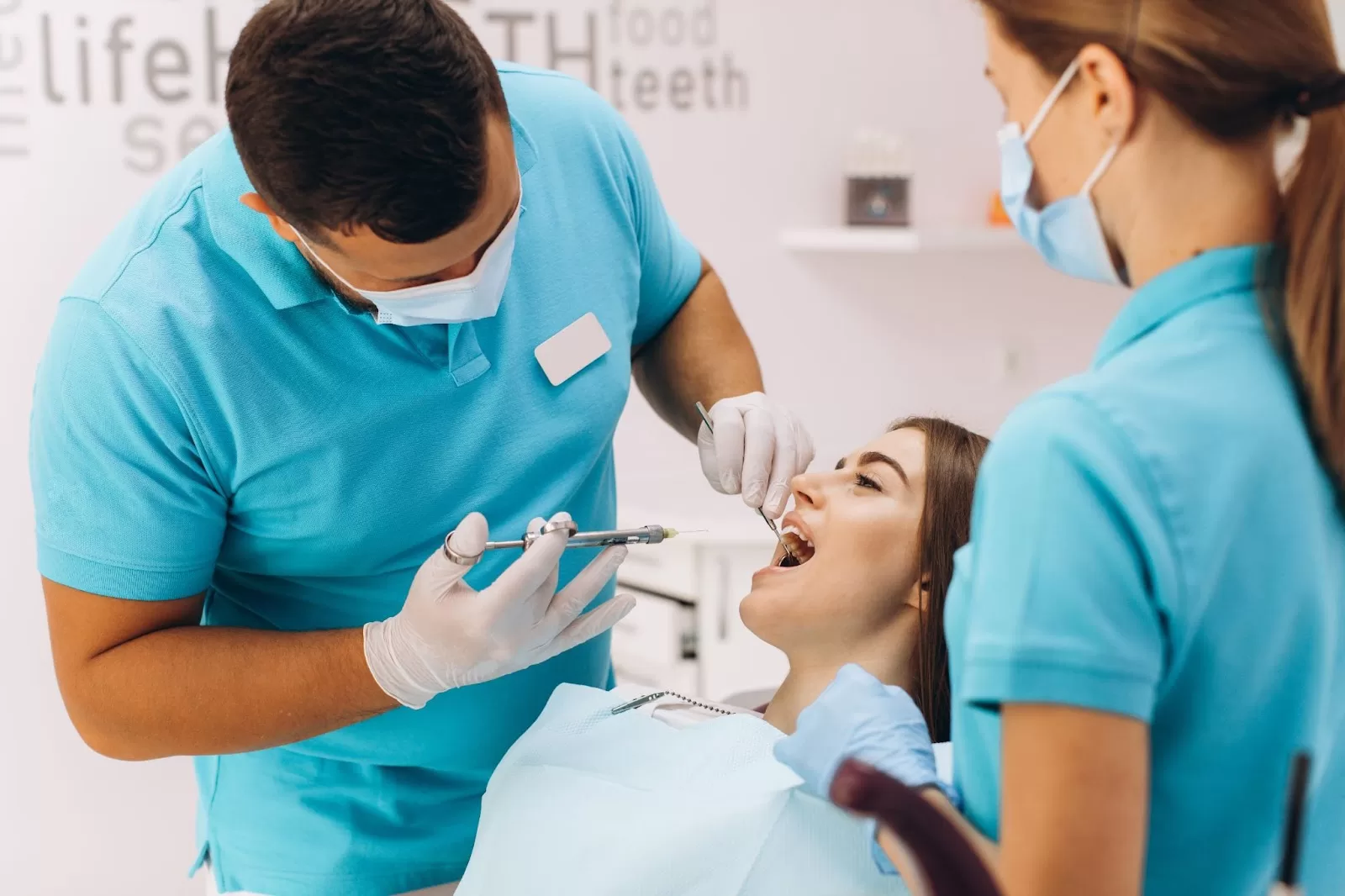 A doctor performing a teeth whitening procedure for a patient with the help of an assistant. 