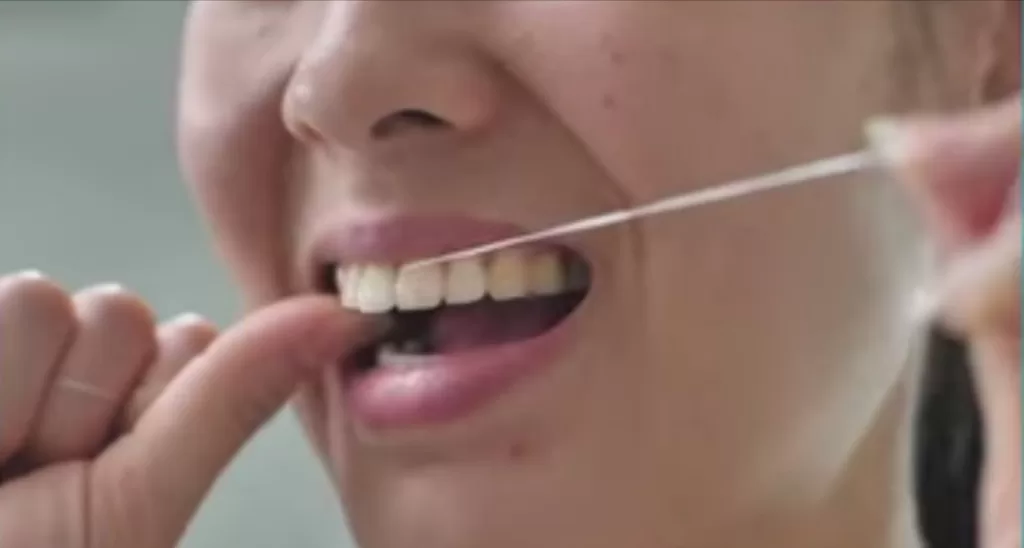 A person uses dental floss to clean between their teeth, promoting a healthy smile.