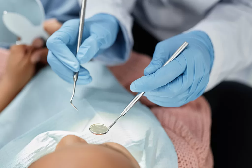 A dentist wearing gloves examines a patient's teeth with dental tools, ensuring a healthy smile.