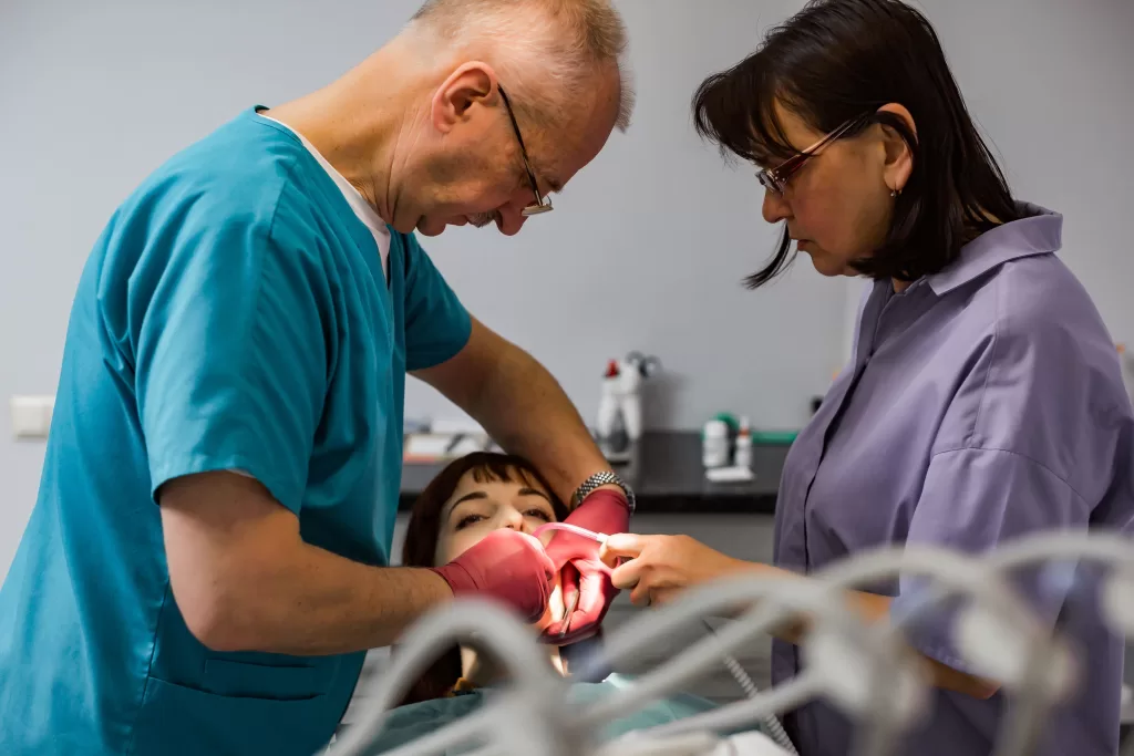 Two dentists working together on a patient, focusing on oral health procedures in a modern clinic. Get expert flossing tips for healthy teeth.