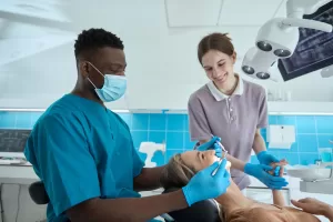 two people helping with the teeth whitening of a lady