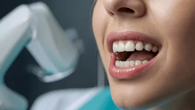 Close-up of a patient's open mouth showing healthy teeth, possibly in preparation for oral biopsies, with a dental device visible in the background.