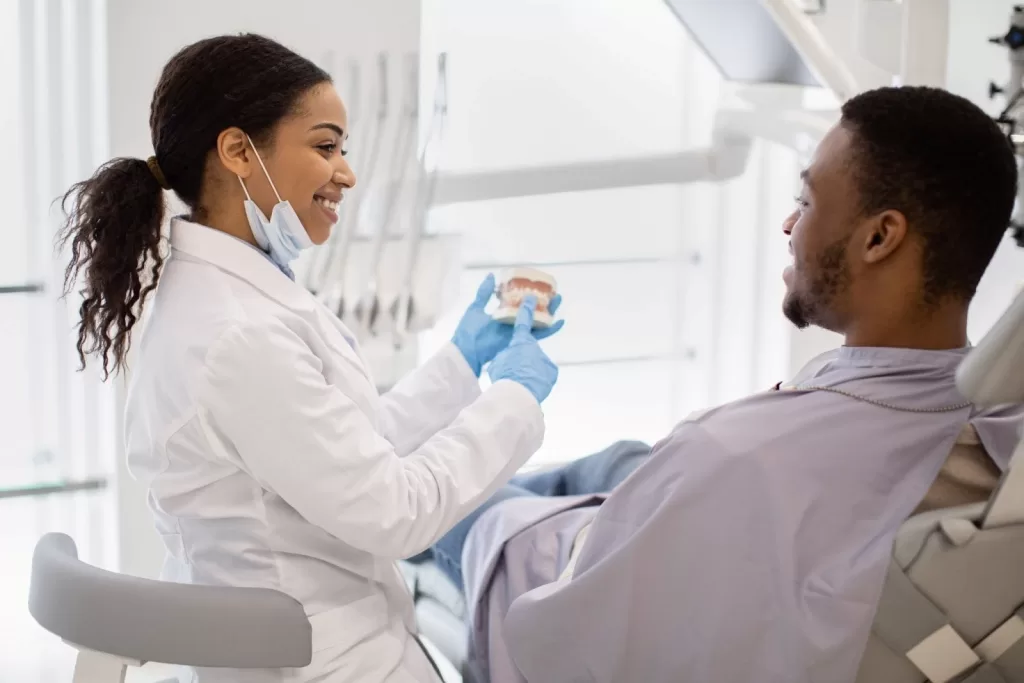 A dentist explaining gum disease prevention using a teeth model.