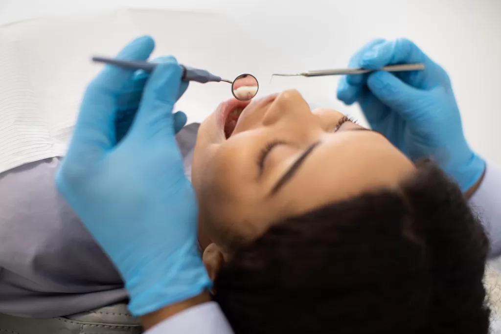 A dentist carefully examines a patient's teeth using dental tools, ensuring a healthy smile.