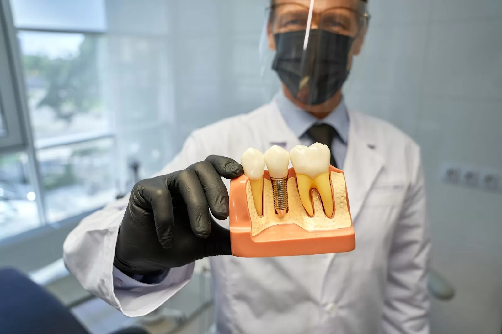 A dentist shows a 3-D model of a dental implant.