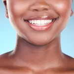 A face showcasing features from modern nose and down, till the collarbones, against a sky blue backdrop.