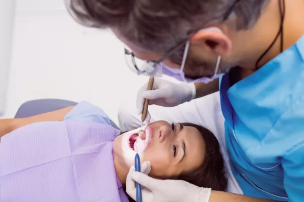 Image of a dentist examining a female patient with tools. 