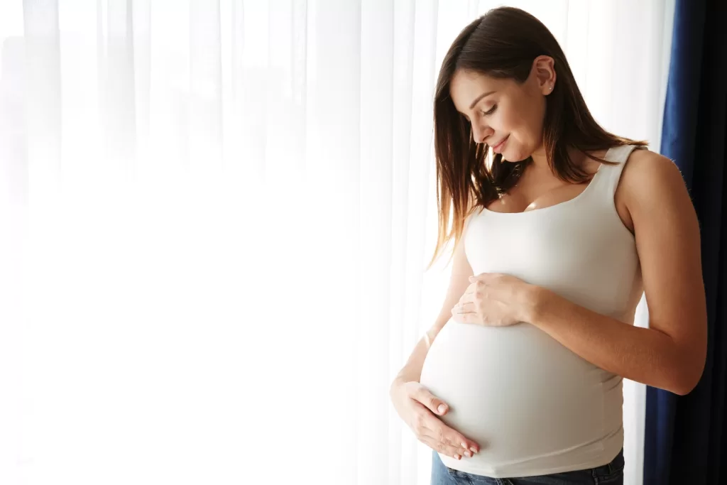 Image of a pregnant woman standing against a white backdrop.
