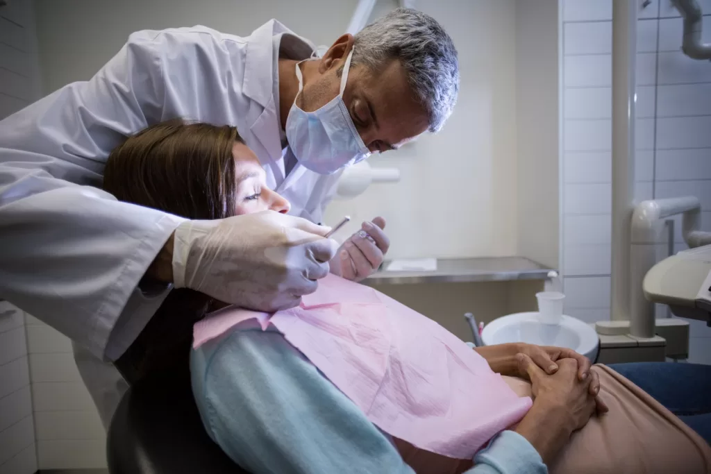 A dentist checking a patient in a dental clinic using various tools.