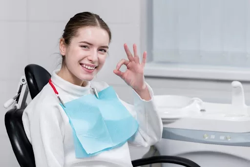 A woman smiles confidently at the camera while seated in a dentist’s clinic in Peapack Gladstone.