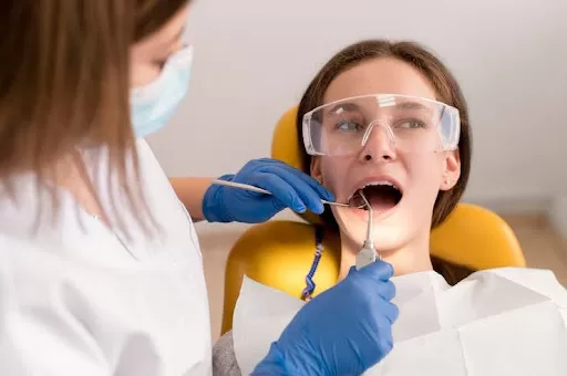 Image of a dentist checking a patient’s mouth for oral well-being.