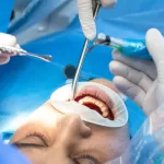 A dentist and assistant with tools examining the patient's mouth.