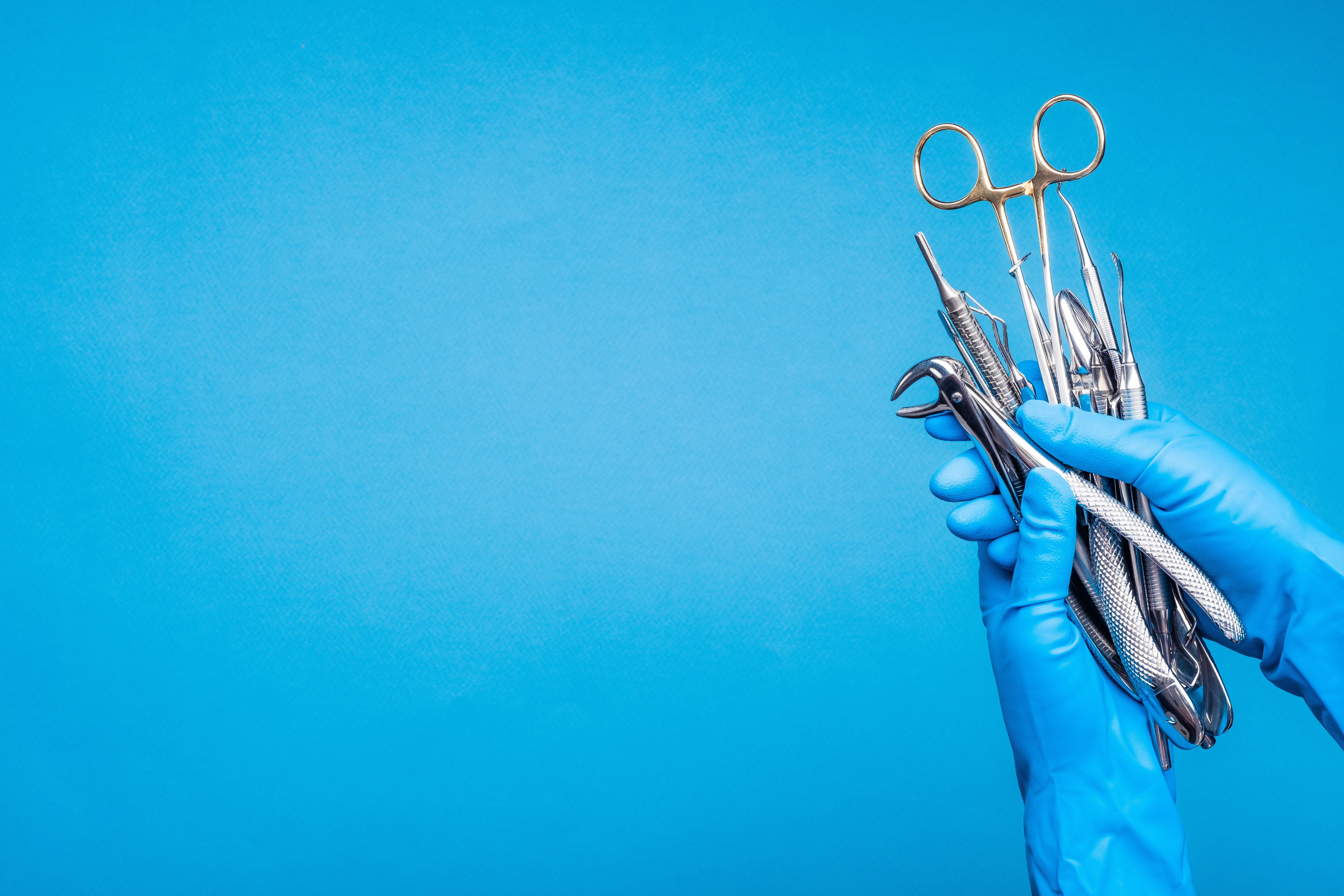 Close-up of a hand holding dental extraction forceps used during oral surgery and tooth extraction procedures.