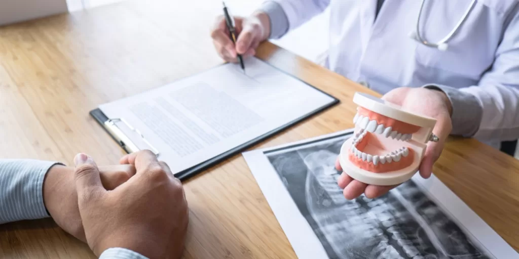 Oral surgeon at Ridge Oral Surgery explaining jaw procedure using model and dental X-ray during anesthesia consultation in New Jersey.