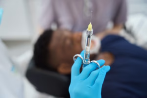 Dentist holding a sterile syringe with dental anesthetic before an oral surgery procedure at Ridge Oral Surgery clinic.