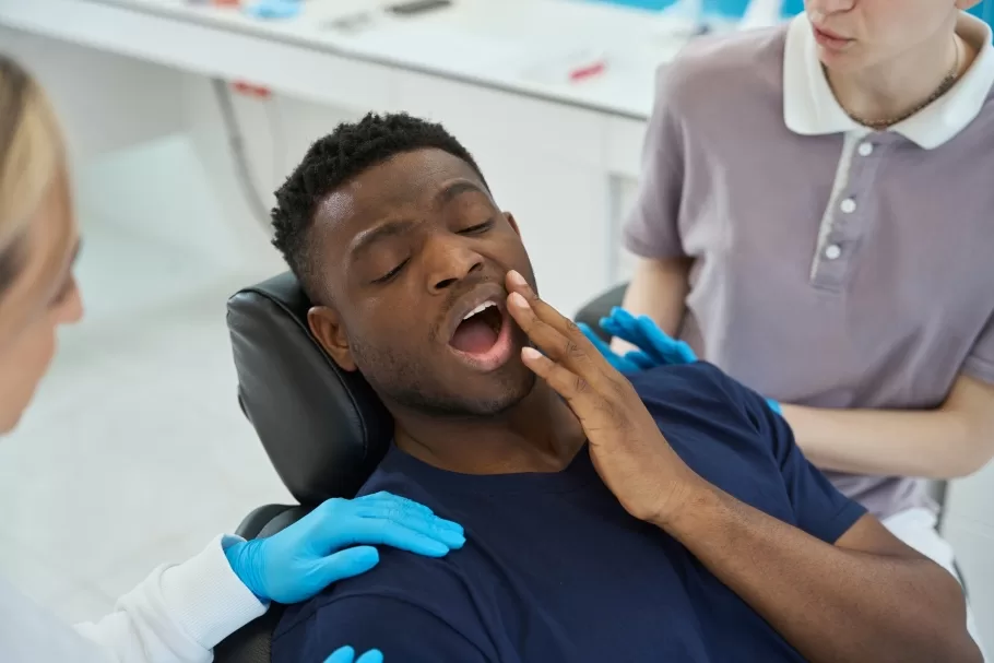 Patient with jaw pain during dental visit at Ridge Oral Surgery in New Jersey, possibly due to wisdom teeth issues.