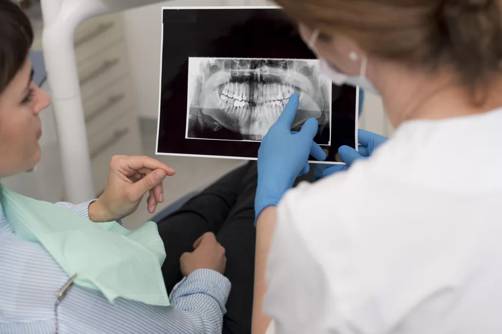 A dentist showing a woman an X-ray of her teeth and jaw alignment.