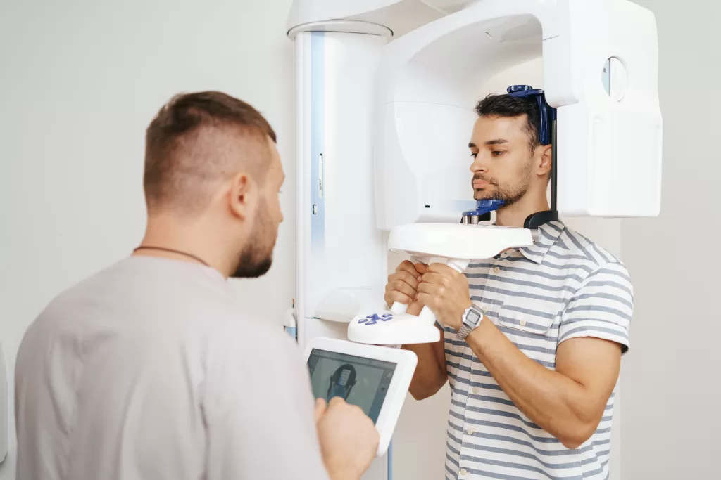 A young man inside a 3D dental scanner for precise surgical planning.