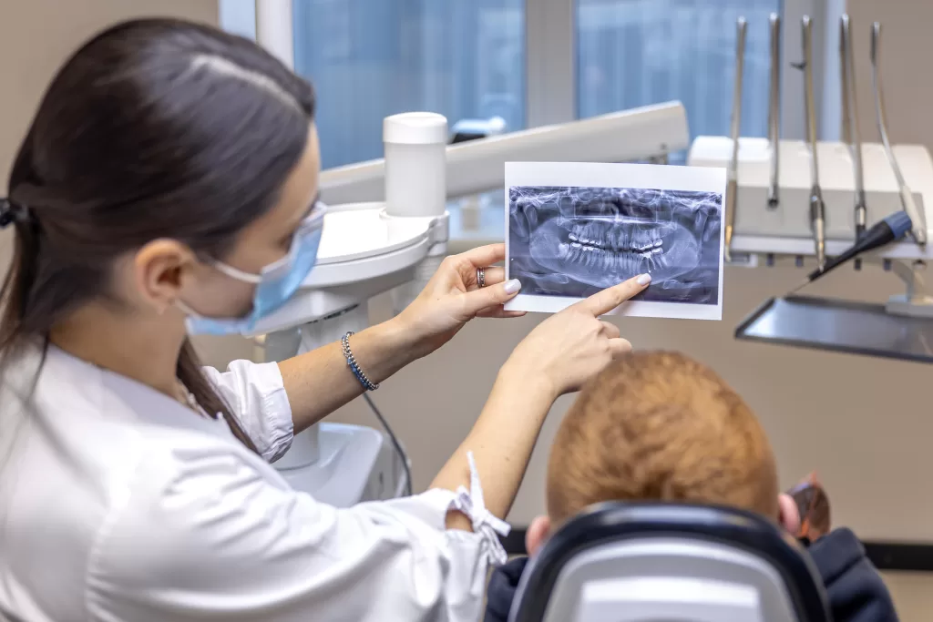 A dentist showing a patient a dental X-ray in a dental clinic, surrounded by surgical instruments.