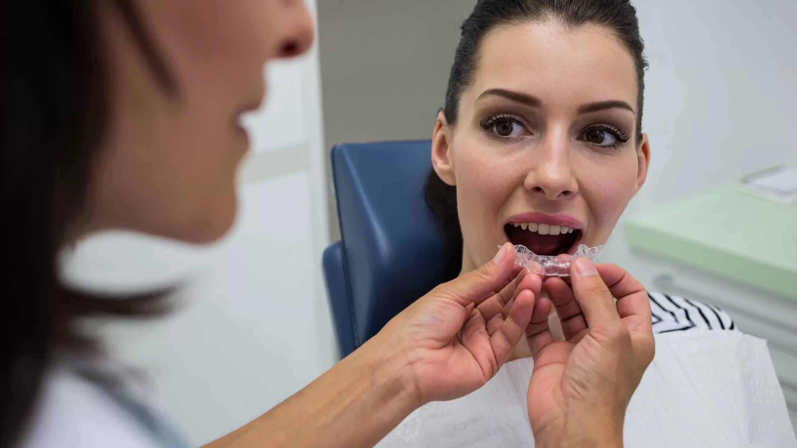 A dentist assisting a patient in wearing invisible braces in a dental clinic.
