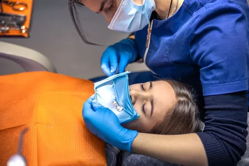 Dentist treating a child’s impacted canine using a rubber dam at Ridge Oral Surgery.