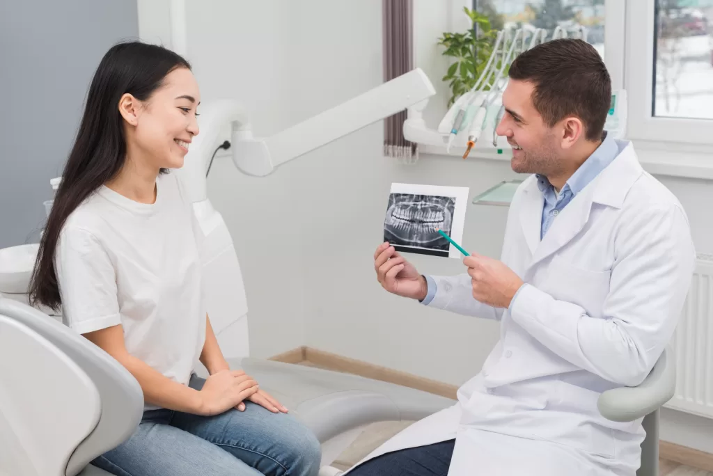 A dentist explaining an X-ray to a woman at the Ridge Oral Surgery clinic.