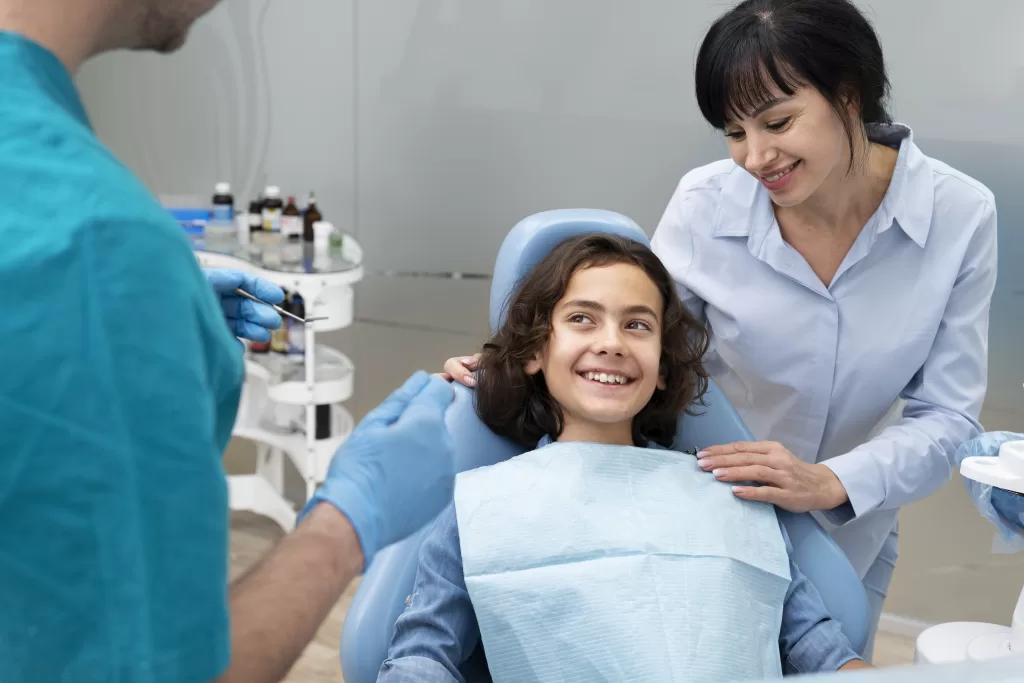 Close-up of a boy being checked on by a dentist, accompanied by an adult woman, at the Ridge Oral Surgery clinic.