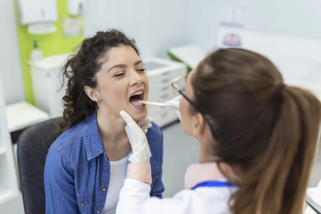 A patient opening her mouth for the dentist to look into it at the Ridge Oral Surgery clinic.