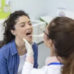 A patient opening her mouth for the dentist to look into it at the Ridge Oral Surgery clinic.