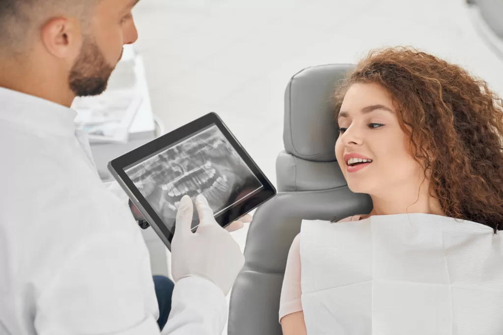 Male dentist showing a dental X-ray to a female patient at Ridge Oral Surgery clinic.