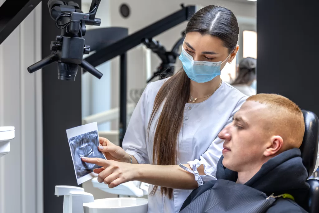 Young dentist showing a patient a dental X-ray at Ridge Oral Surgery clinic.