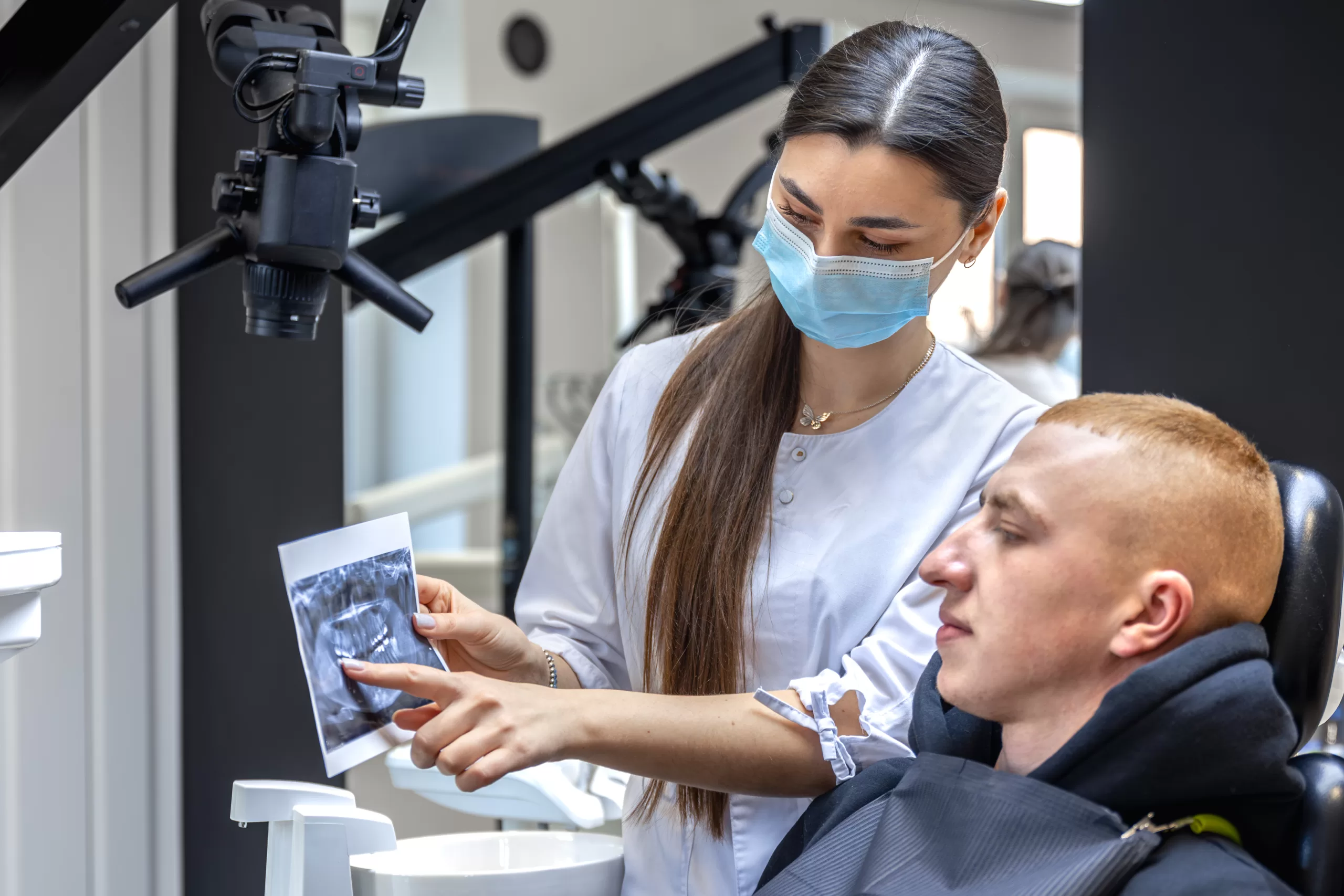 Young dentist showing a patient a dental X-ray at Ridge Oral Surgery clinic.