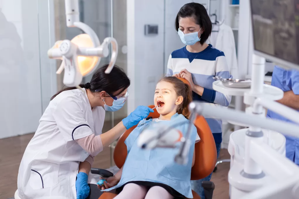 A dentist using an angled mirror to examine a boy's teeth at the Ridge Oral Surgery clinic.
